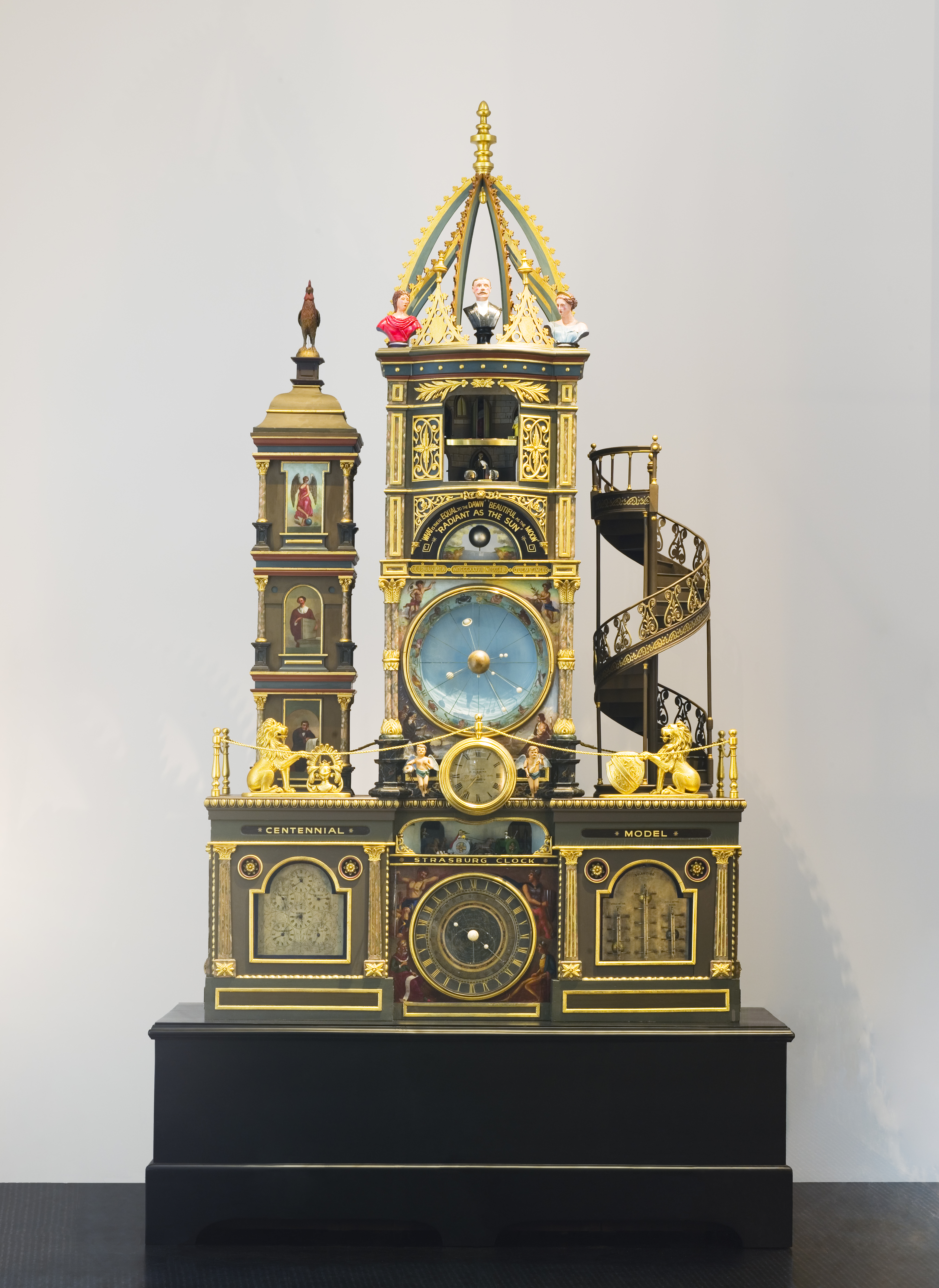 A four-metre high ornate gold clock with a tall centre tower with a procession of the 12 Apostles inside an alcove, a shorter tower on the left and a spiral staircase on the right.